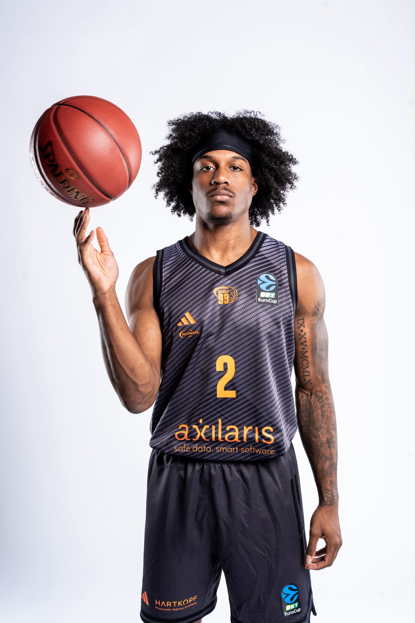 Stefan Smith holding a basketball balanced on one finger, wearing his basketball uniform